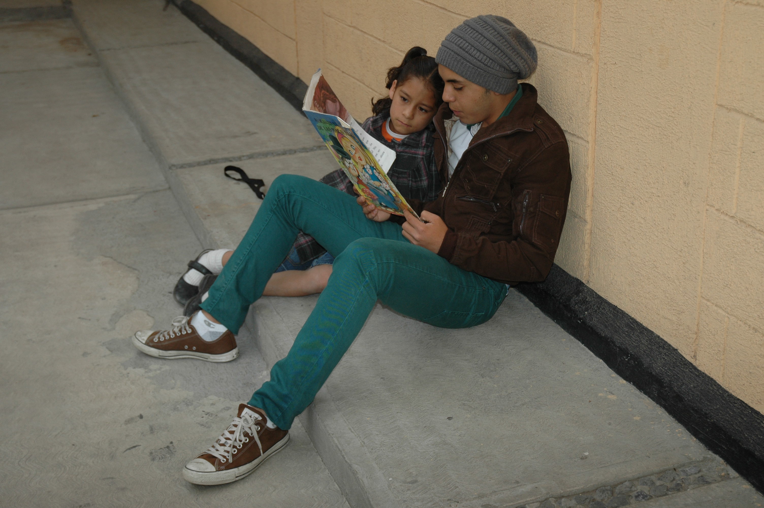 teen and child reading outdoor wall