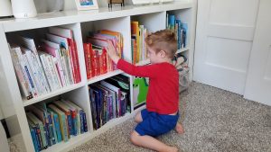 Boy sitting by book shelf