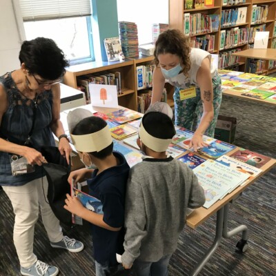 La coordinadora de voluntarios Jessy ayuda a los estudiantes a comprar los libros de Summer Success en Wooten Elementary.